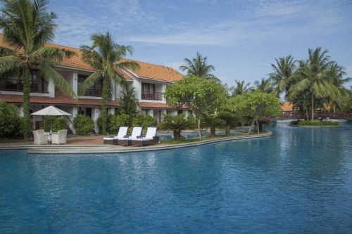 un complexe avec une piscine d'eau et des palmiers dans l'établissement Radisson Blu Resort Temple Bay Mamallapuram, à Mahabalipuram