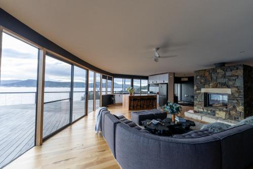 uma sala de estar com um sofá e uma grande janela em Siren Tasmania em White Beach