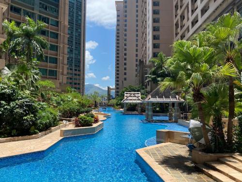 einen Pool in einer Stadt mit Palmen und Gebäuden in der Unterkunft Rambler Oasis Hotel in Hongkong