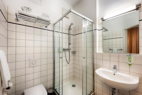 La salle de bains est pourvue d'une douche en verre et d'un lavabo. dans l'établissement martas Hotel Berlin-Mitte, à Berlin