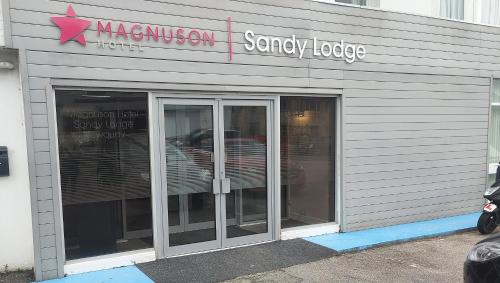 uma loja com duas portas de vidro e um cartaz em Magnuson Hotel Sandy Lodge Newquay em Newquay