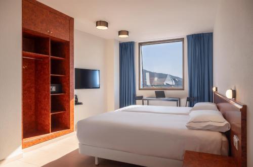 a bedroom with a large white bed and a window at Hesperia Sant Joan in Sant Joan Despí