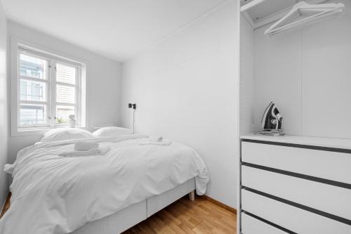 Homerentals Apartments - Behind Bryggen & historic cobblestone streets في بيرغِن: غرفة نوم بيضاء بها سرير ونافذة