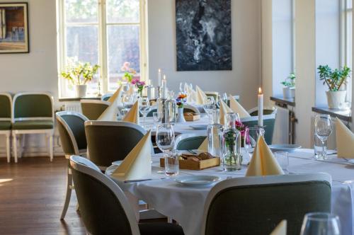 a dining room with a long table with white tables and chairs at Skeviks Gård in Gustavsberg