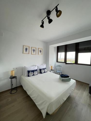 1 dormitorio blanco con 1 cama blanca grande y 2 almohadas en Apartamentos Matilda, en Conil de la Frontera