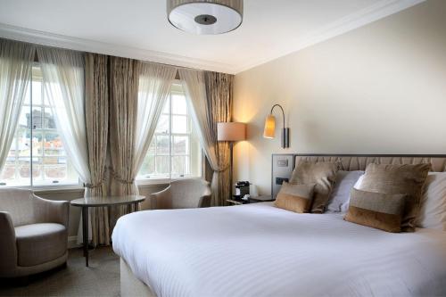 een slaapkamer met een groot wit bed en een stoel bij Castle Hotel Windsor in Windsor