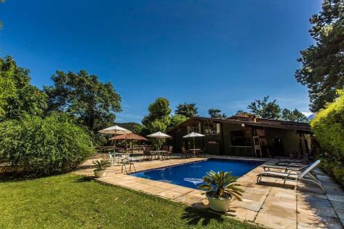 un patio trasero con piscina y una casa en Hotel Colinas de Petropolis en Petrópolis