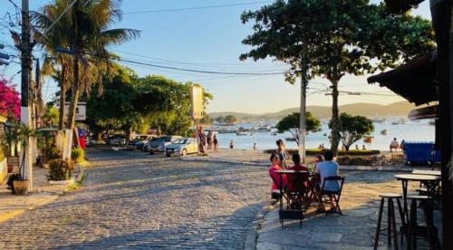 um grupo de pessoas sentadas numa mesa perto da água em Pousada Americas em Búzios