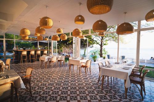 a restaurant with white tables and chairs and windows at Sadef Akkonak in Amasra