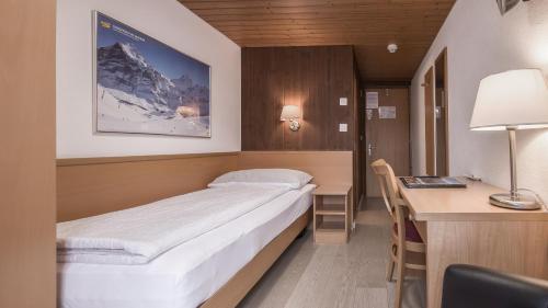 um quarto com uma cama e uma secretária com um computador em Hotel Rössli em Interlaken