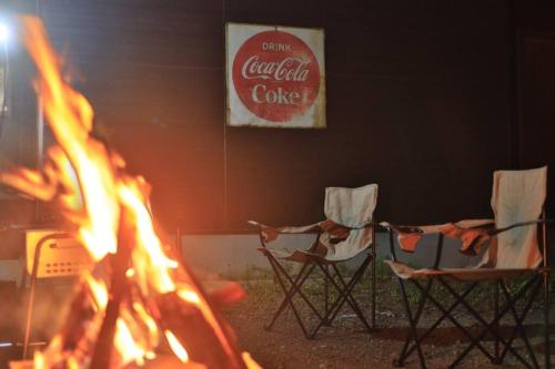 3 Stühle sitzen um ein Feuer in einem Raum in der Unterkunft Starry Sky Cottage 15 in Kitami