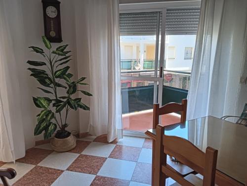 un comedor con una mesa de cristal y una planta en Casa Delfin, en Punta Umbría