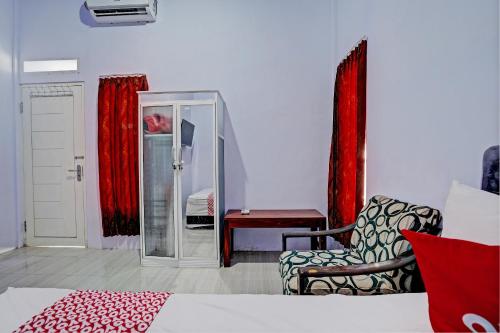 una camera con letto, sedia e specchio di OYO 92817 Niza Guesthouse Syariah a Banyuwangi