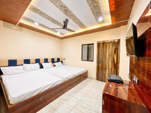 1 dormitorio con 1 cama y TV de pantalla plana en SATYAM PALACE guest house ! UJJAIN सत्यम पैलेस गेस्ट हाउस சத்யம் பேலஸ் விருந்தினர் மாளிகை సత్యం ప్యాలెస్ గెస్ట్ హౌస్ fully-Air-Conditioned hotel at prime location with wifi & off site Parking availability, near-Mahakal-Temple-&-Railway-station en Ujjain