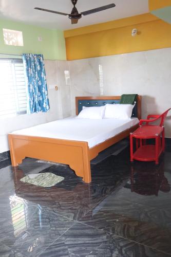 a bedroom with a bed and a red chair at Jagannatha Guest House in Puri