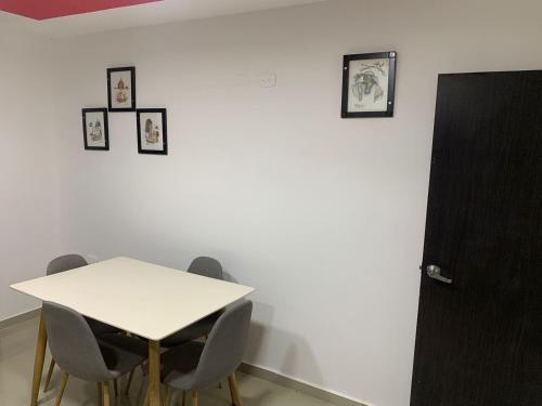 une table blanche avec des chaises et des photos sur un mur dans l'établissement APARTAMENTO EN VALLEDUPAR, à Valledupar