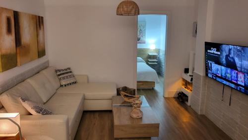 een woonkamer met een bank en een flatscreen-tv bij Apartamento EL REAL - Espartinas - SEVILLA in Espartinas