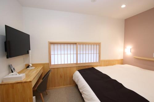 a bedroom with a bed and a desk and a television at みつくりHOTEL in Tuyama