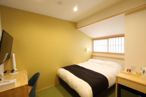 a bedroom with a bed and a desk and a window at みつくりHOTEL in Tuyama