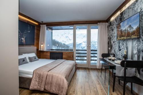 um quarto com uma cama, uma secretária e uma janela em DEER LODGE em Breuil-Cervinia