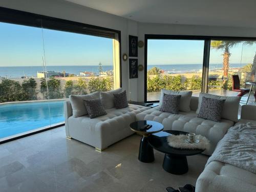 ein Wohnzimmer mit einem weißen Sofa und einem großen Fenster in der Unterkunft Luxury Villa Jack Beach Resort Ocean Oasis View Panoramic in Casablanca