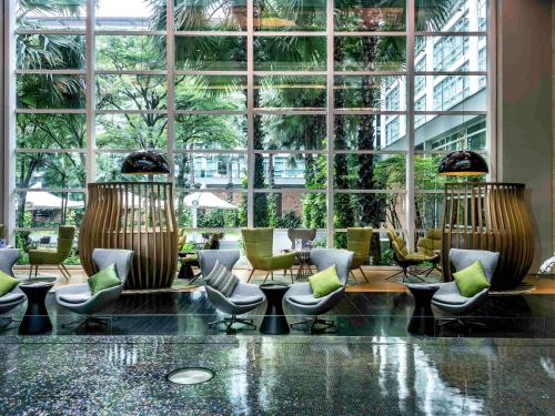 een lobby met stoelen en tafels en een groot raam bij Pullman Bangkok King Power in Bangkok