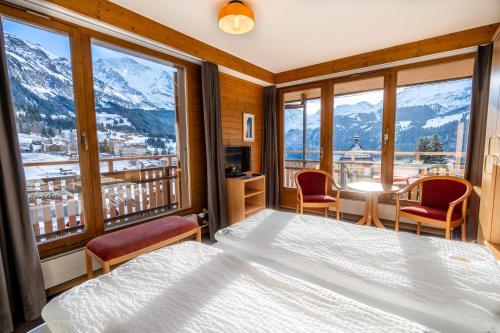 um quarto com uma cama e uma varanda com montanhas em Hotel Jungfraublick em Wengen