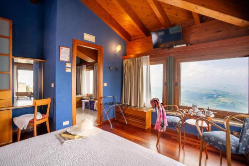 1 dormitorio con paredes azules, mesa y ventana grande en Hotel Cesare en San Marino