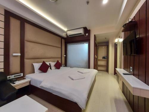 1 dormitorio con 1 cama blanca grande y TV en New Gitanjali Hotel, New Digha, en Digha