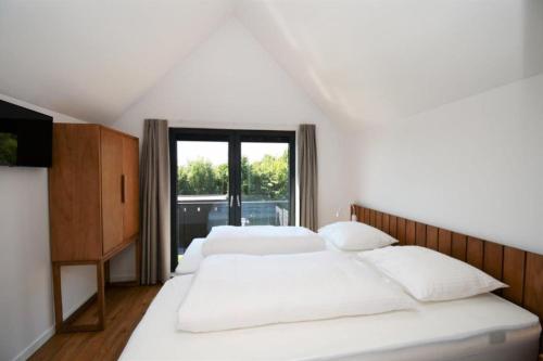 two beds in a room with a large window at Skylgerduin in Midsland