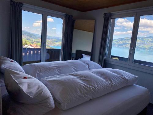 two white beds in a room with large windows at Eva's Seeblick in Krattigen