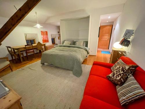 1 dormitorio con 1 cama y 1 sofá rojo en Casa Barbun - Soglio GR en Soglio