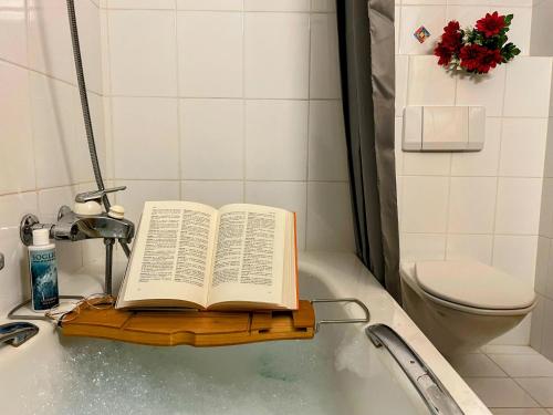 un libro abierto sobre una bandeja de madera en la bañera en Casa Barbun - Soglio GR en Soglio