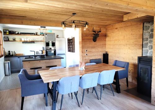 una sala da pranzo con tavolo in legno e sedie blu di Chalet Mondego, paisible et tout confort a Gérardmer