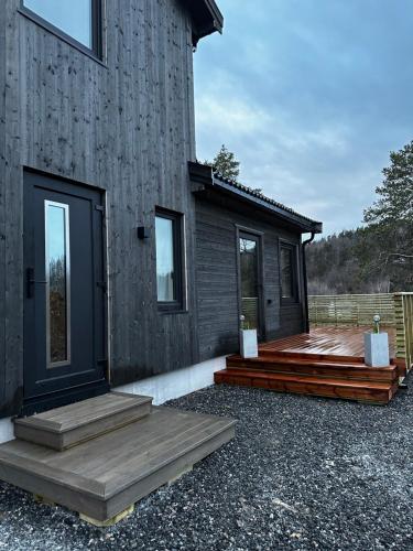 uma casa com um alpendre em madeira e um deque em Familievennlig Apartment em Tvedestrand