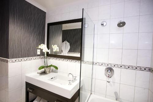 bagno bianco con lavandino e specchio di Distinction Coachman Hotel, Palmerston North a Palmerston North