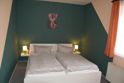 a bedroom with a white bed with a green wall at Gasthaus B r o c k e n h e x e in Elbingerode