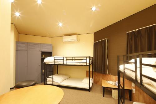 Zimmer mit 2 Etagenbetten und einem Tisch in der Unterkunft Starry Sky Cottage 16 - Vacation STAY 96148v in Kitami