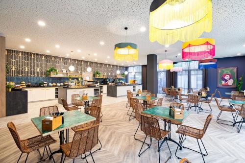 Holiday Inn - the niu, Flower Konstanz, an IHG Hotel في كونستانز: مطعم بطاولات وكراسي ومطبخ