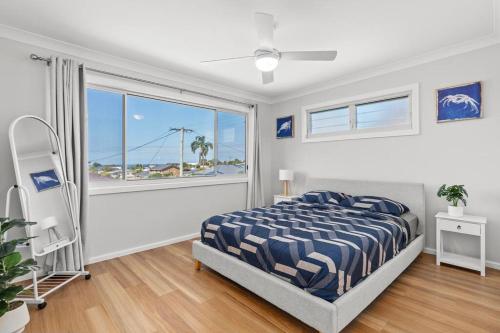 1 dormitorio con cama y ventana grande en Pacific Breeze en Caves Beach