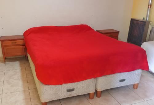 um cobertor vermelho numa cama num quarto em La Chacra departamentos x dia em Río Gallegos