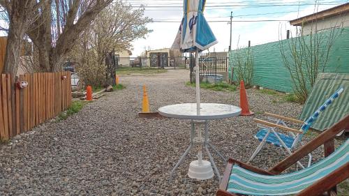 uma mesa e duas cadeiras e um guarda-sol num quintal em La Chacra departamentos x dia em Río Gallegos