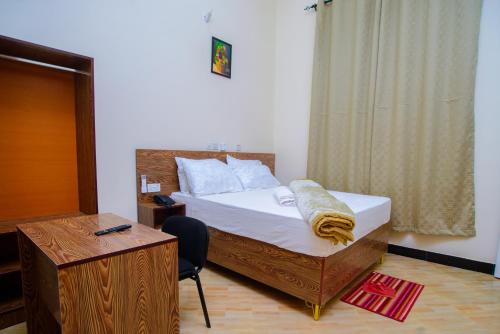 een slaapkamer met een bed, een bureau en een stoel bij Paco Lodge in Dodoma