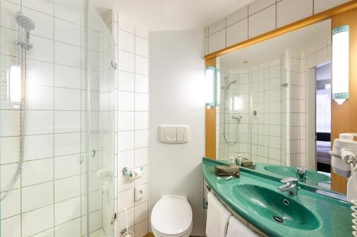 baño con lavabo verde y aseo en Hotel Ibis Bregenz en Bregenz