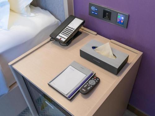 a desk with a bed and a phone and a tablet at Lavande Hotel Beijing International Exhibition Heping Xiqiao Metro Station in Beijing