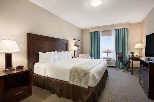 Ramada by Wyndham Emerald Park/Regina East tesisinde bir odada yatak veya yataklar