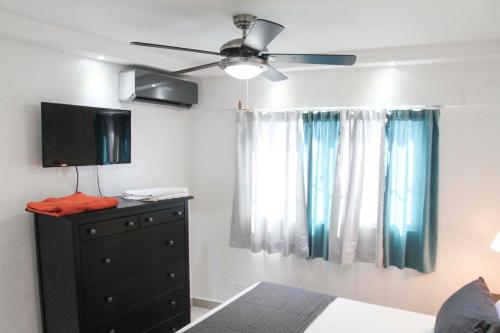 1 dormitorio con ventilador de techo y vestidor con TV en City Caribbean Hotel Boutique en Santo Domingo