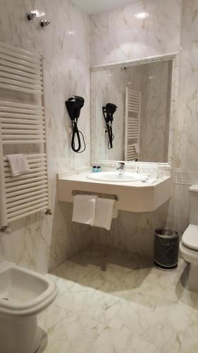 La salle de bains blanche est pourvue d'un lavabo et de toilettes. dans l'établissement Hotel Valle Las Luiñas, à Soto de Luiña