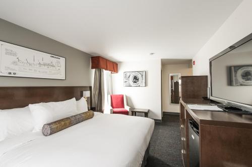 um quarto de hotel com uma cama e uma televisão em Edgewater Hotel em Whitehorse