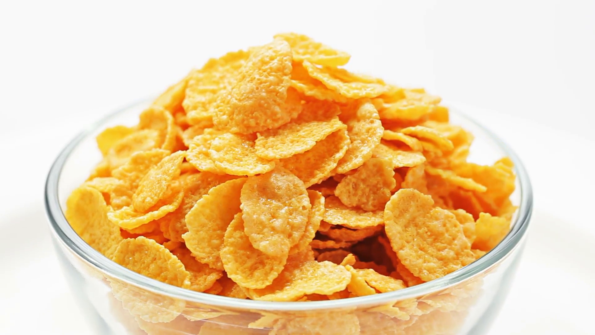 Corn flakes heap in a glass bowl rotating over white, loop ready Stock  Video Footage.